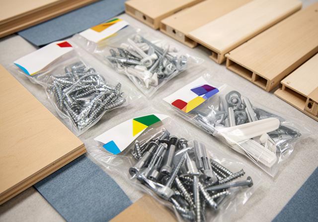 Small labelled bags of screws and shelf fittings arranged beside dismantled wardrobe panels